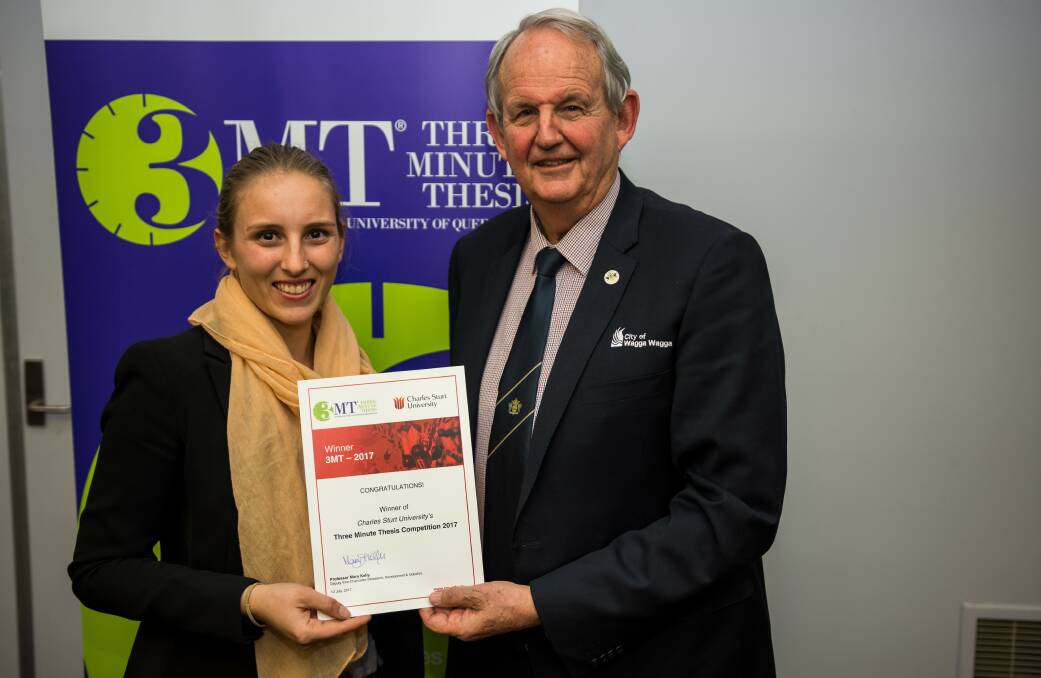 Charles Sturt University PhD student Cara Wilson receiving an award for a three minute thesis on her work in preventing waste in the beef supply chain from the Mayor of Wagga Wagga, councillor Greg Conkey. Photo: Mitchell Lamm
