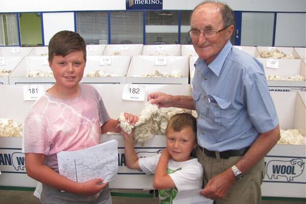 Elaine wool grower Tim Wells, with grandsons Jack and Cooper Jones, inspect a clip of the 14.8 micron wool which sold at 1449 cents/kilogram.