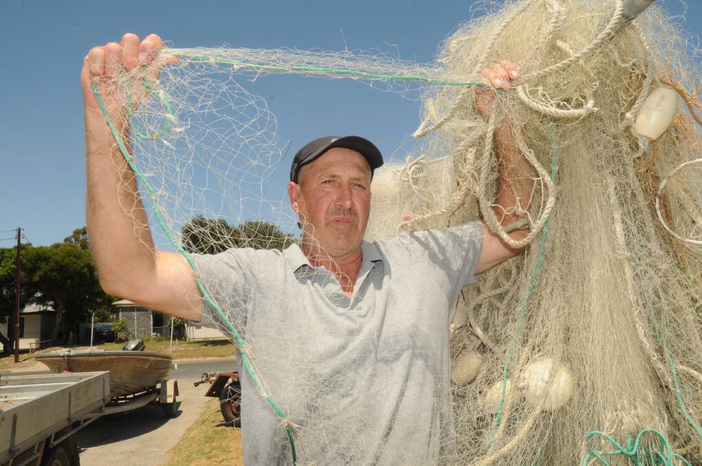 Meningie fisher Tim Richards shows off nets damaged by long-nosed fur seals.