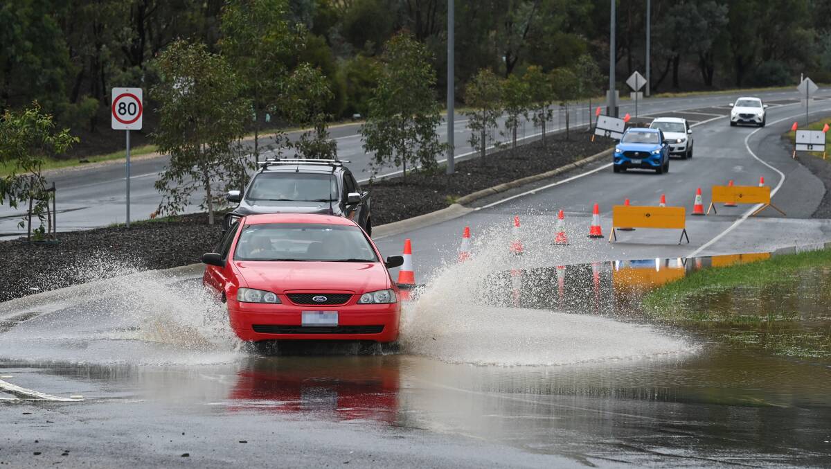 Vehicles travel through water over the road at Bandiana Link, Wodonga, after heavy rainfall caused flash flooding. Picture by Mark Jesser