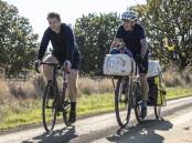 PEDDLING ALONG: M.J. Bale chief executive riding along with cyclist Grant Meddock, who delivered 35kg of which over 200 kilometres to Hobart by bicycle from Kingston Superfine Farm in the Tasmanian Midlands.
