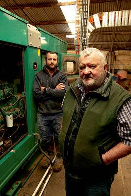 POWER WOES: Bruce and son Martin Knowles on their property in Tyrendarra, standing next to the three phase power generators that help keep their dairy operational in case of an outage. Photo by Chris Doheny