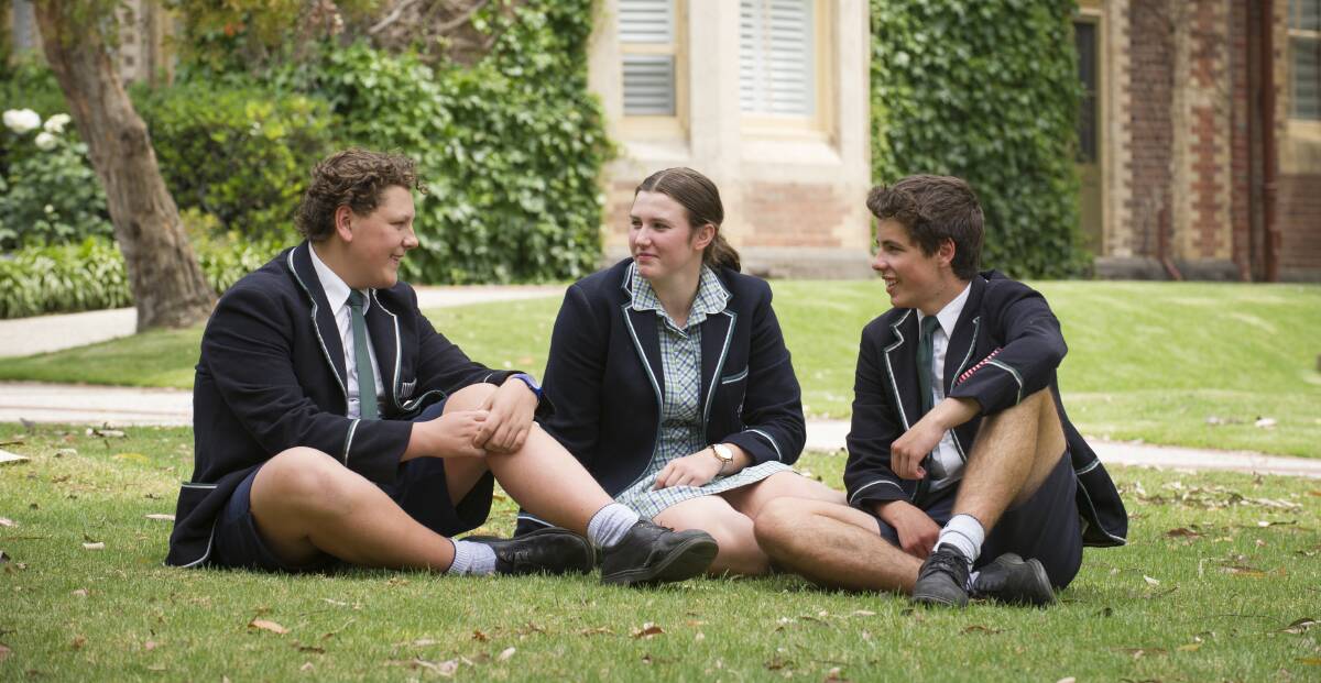 DOWN-TIME: A group of The Geelong College Boarders relax in the grounds of the school at lunchtime.