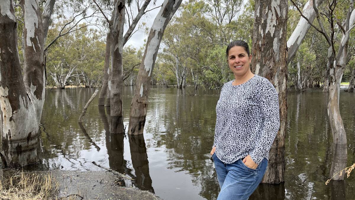 Dairy farmer Monique Bryant, Kaarimba, stands by the Broken Creek on her northern Victorian property. Water levels on the trees to the left of her show the river's peak height.