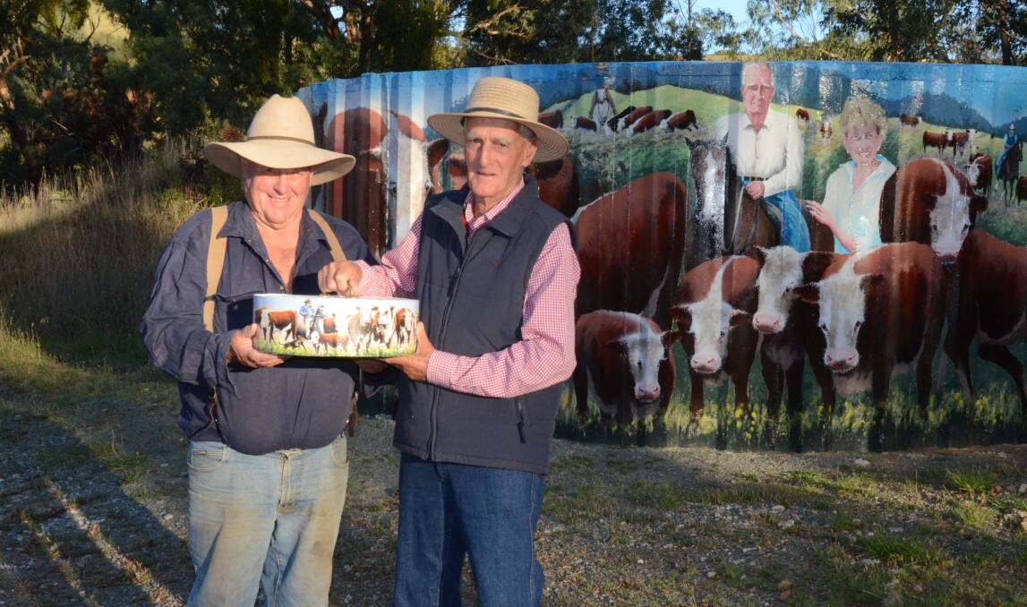 Ensay graziers Phillip 'Bluey' Commins, Nunniong Herefords, and Barry Newcomen, Newcomen Herefords, stand in front of a water tank which features both principals and their iconic Hereford cattle. Picture by Bryce Eishold