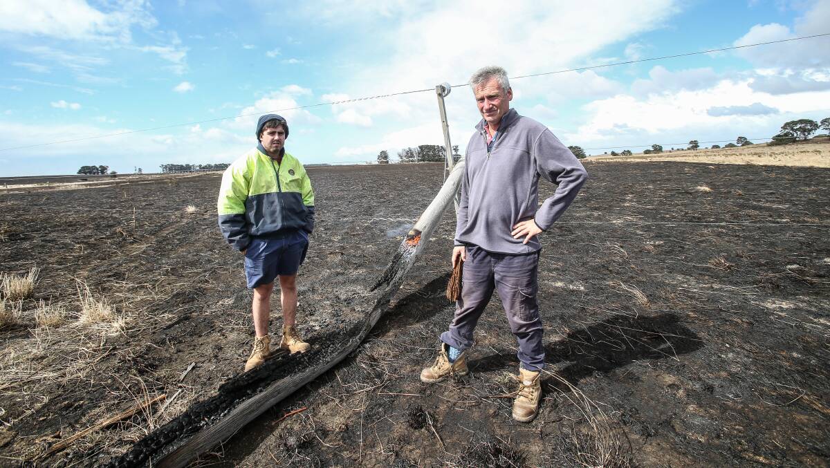 Jack Kenna Junior and Bernie Harris with the smouldering remains of the pole that snapped and sparked a fire at The Sisters on St Patrick's Day last year.