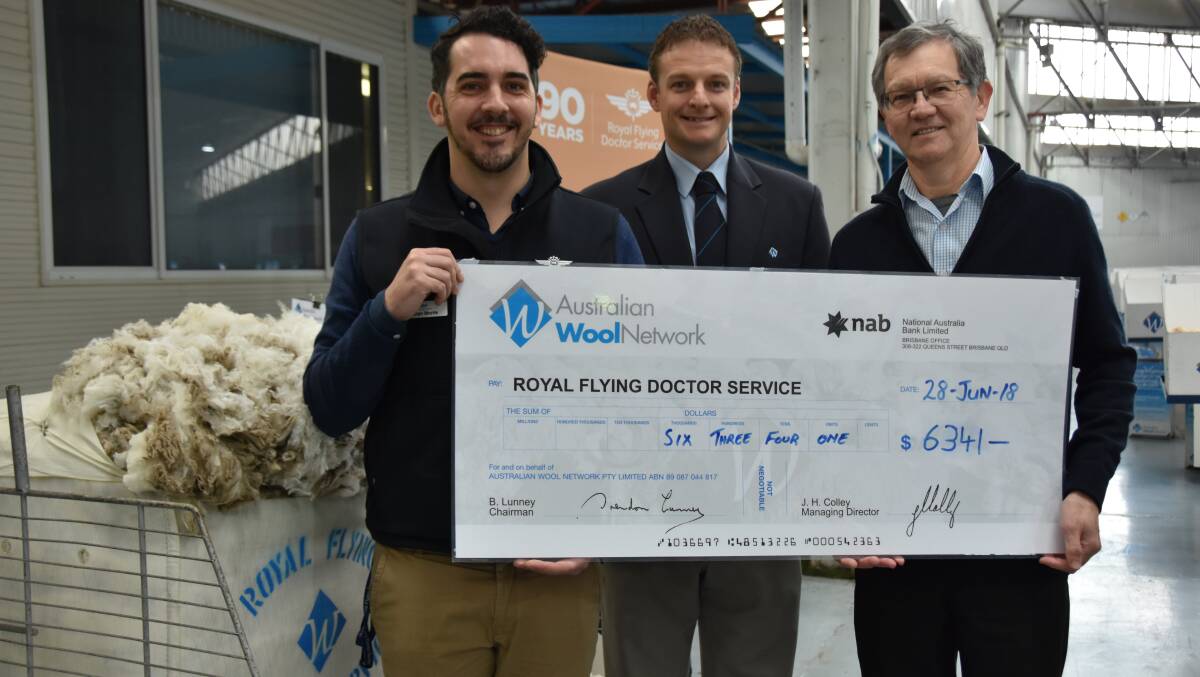 Royal Flying Doctor Service's Rohan Morris, Australian Wool Network Victorian state manager Kelvin Shelley, and Modiano Victorian wool manager Lou Morsch, with the $6341 cheque at the Melbourne woolstores.