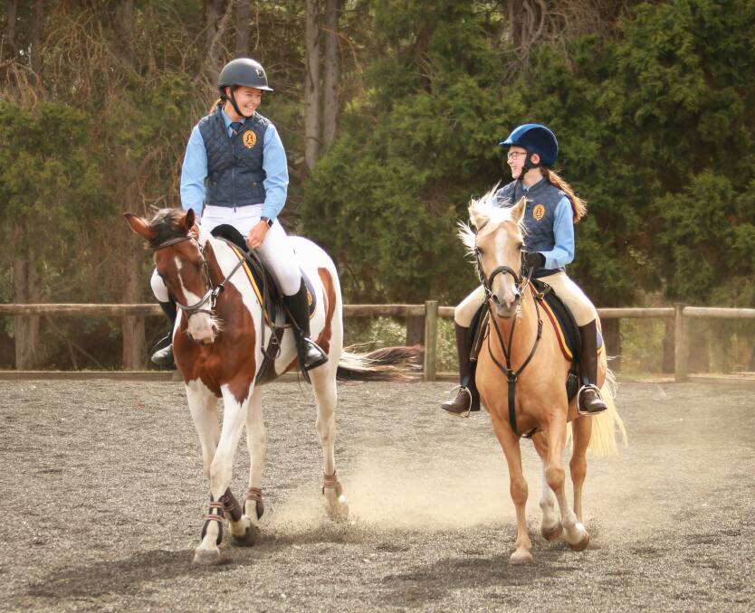 OUTDOORS: Year 12 boarding student Georgia Hodgetts and Year 5 student Amelie Hiscock enjoying the benefits of the college equestrian program.