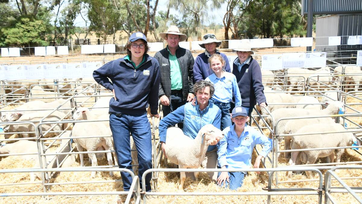 Top-priced ram lamb held by Cloven Hills stud principal Chris Dorahy, pictured with Nutrien Casterton agent Rick Smith (second from left), buyer Marita Cox, and the Cloven Hills team Harry, Bridie, Kate and Rupert (kneeling).
