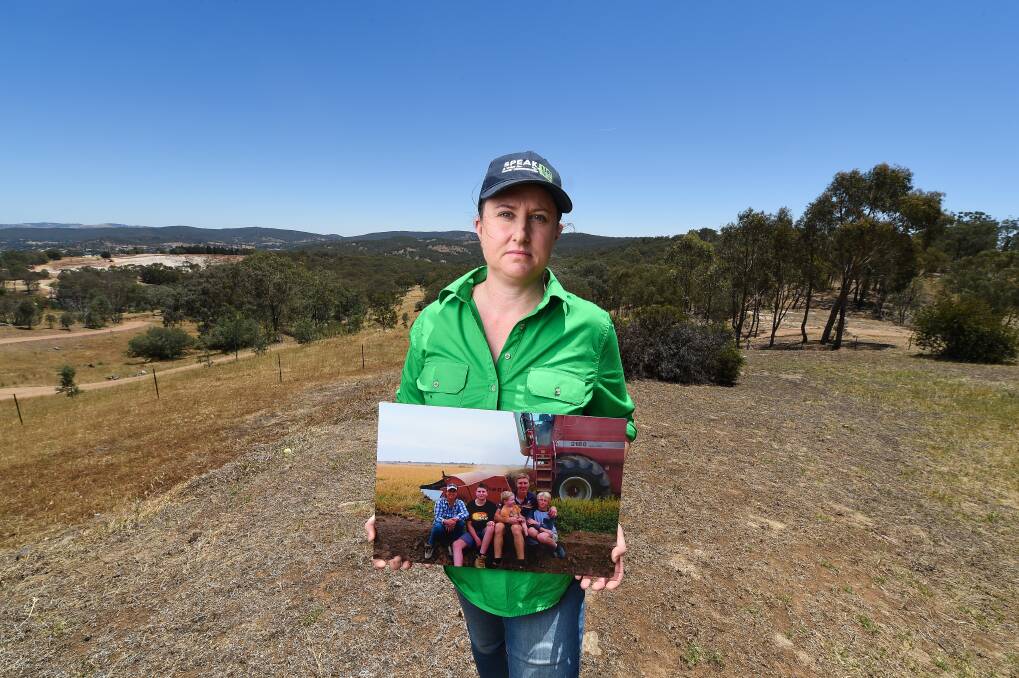 LOOKING BACK: Shelley Scoullar holds a picture of her family - husband Paul and sons Hayden, 14, Lachie, 4, and Jack, 12 - taken in April 2019 during their last rice harvest on her farm. 